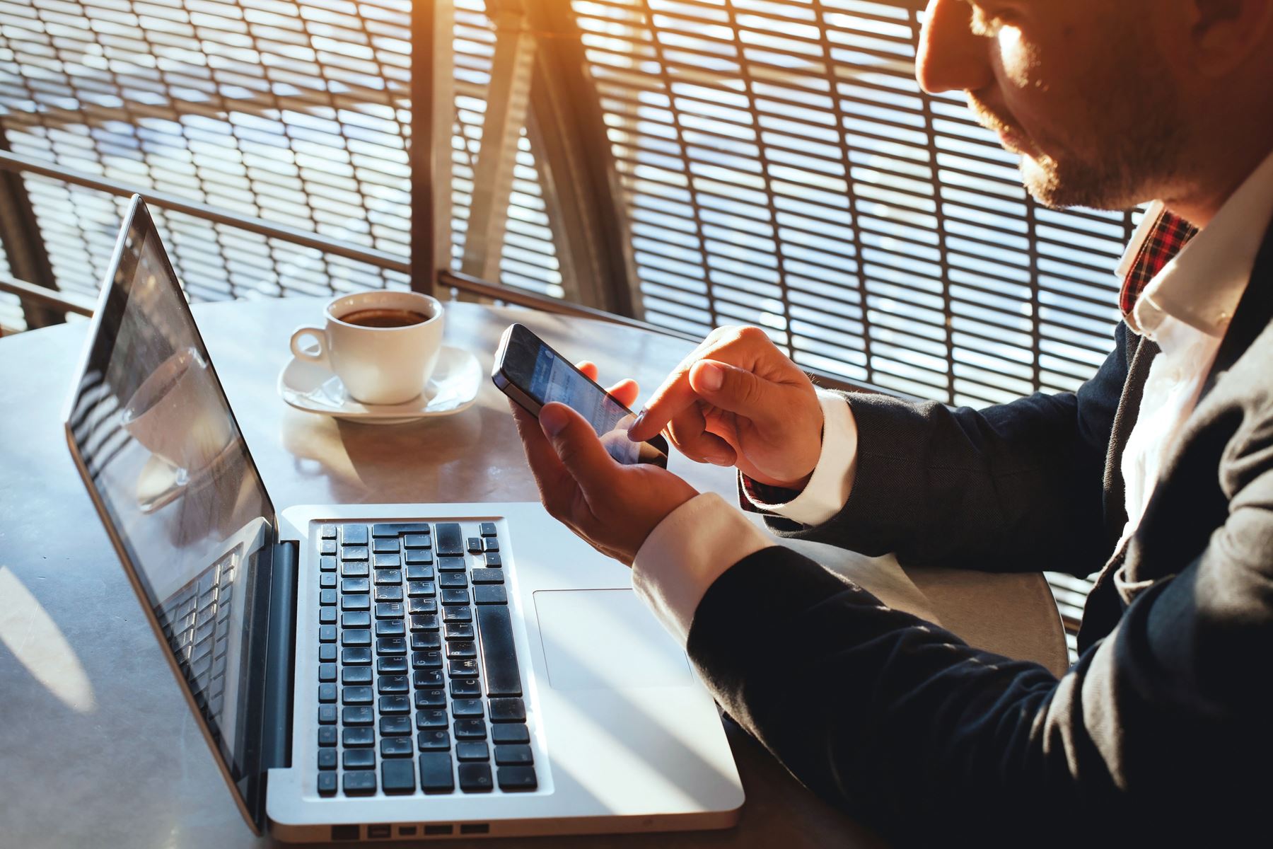 Business man sitting at laptop using phone